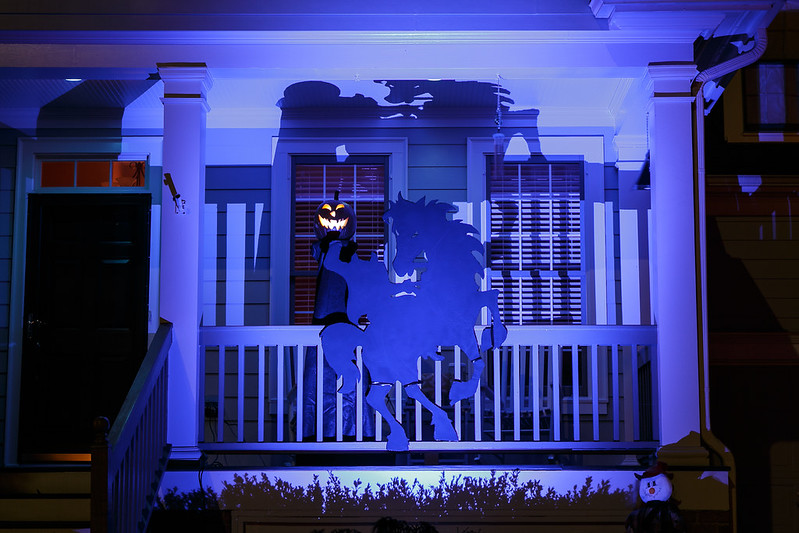 Headless Horseman cutout decoration on a porch, lit with blue light for Halloween decor
