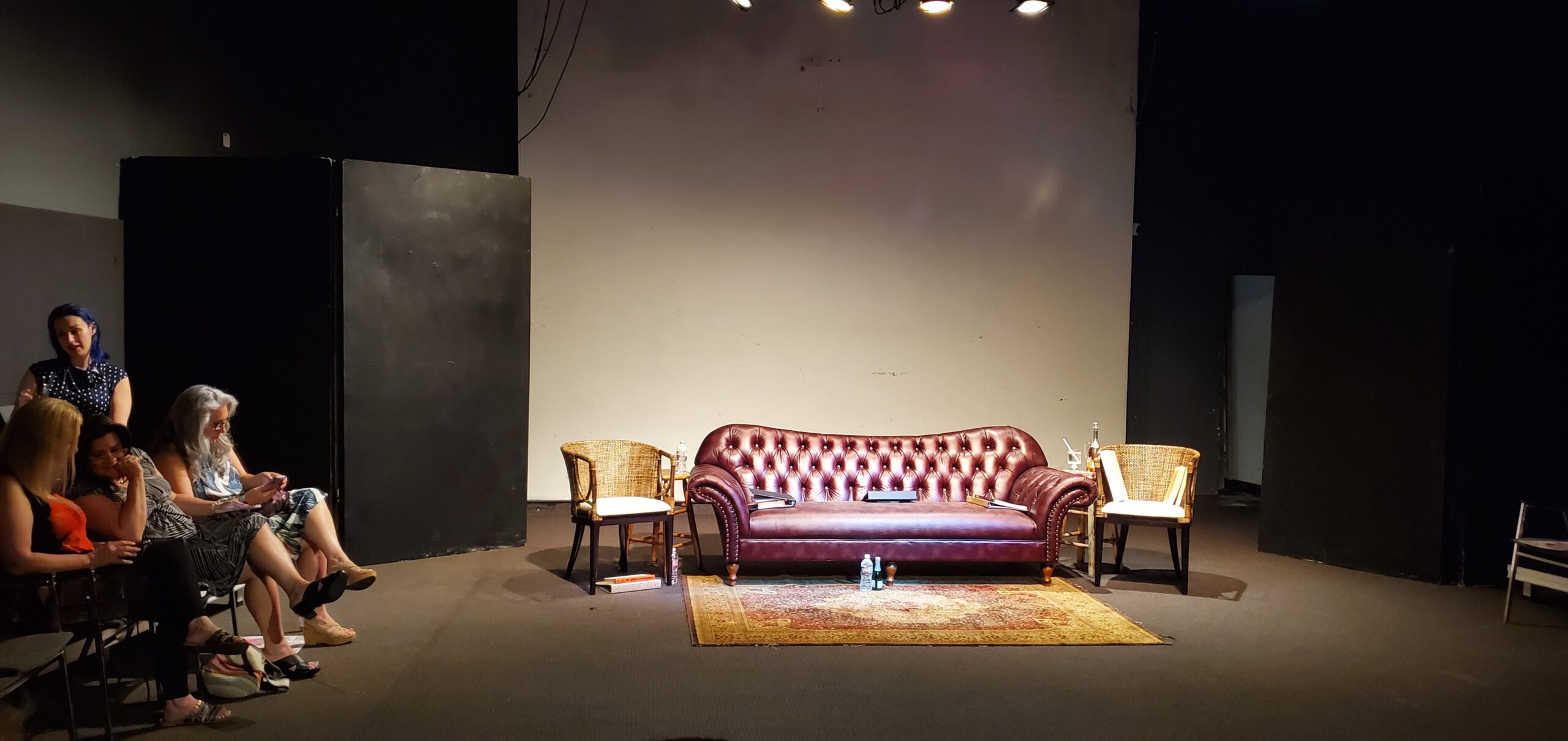 An open stage, with an empty red couch