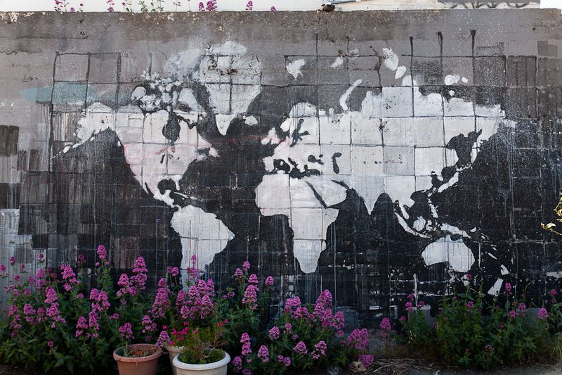 A mural of the world, created in negative space on a dirty wall.