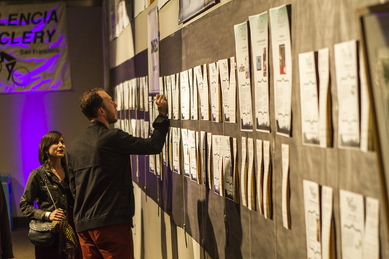 A patron bidding on a silent auction, with many pages taped to a wall.