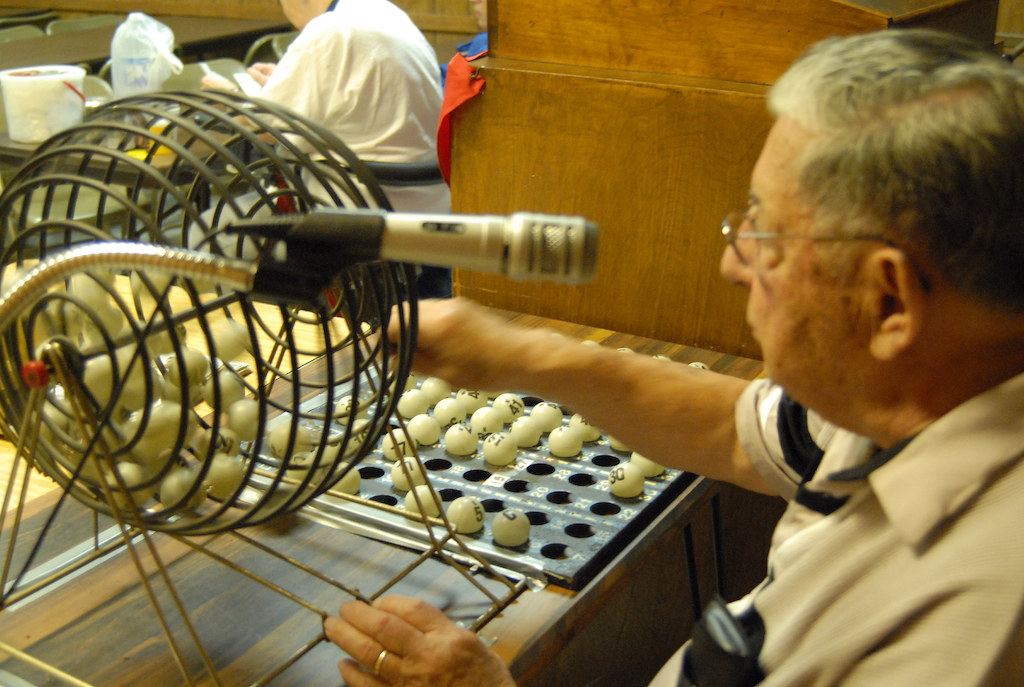 An older gentleman, turning a cage full of bingo balls.